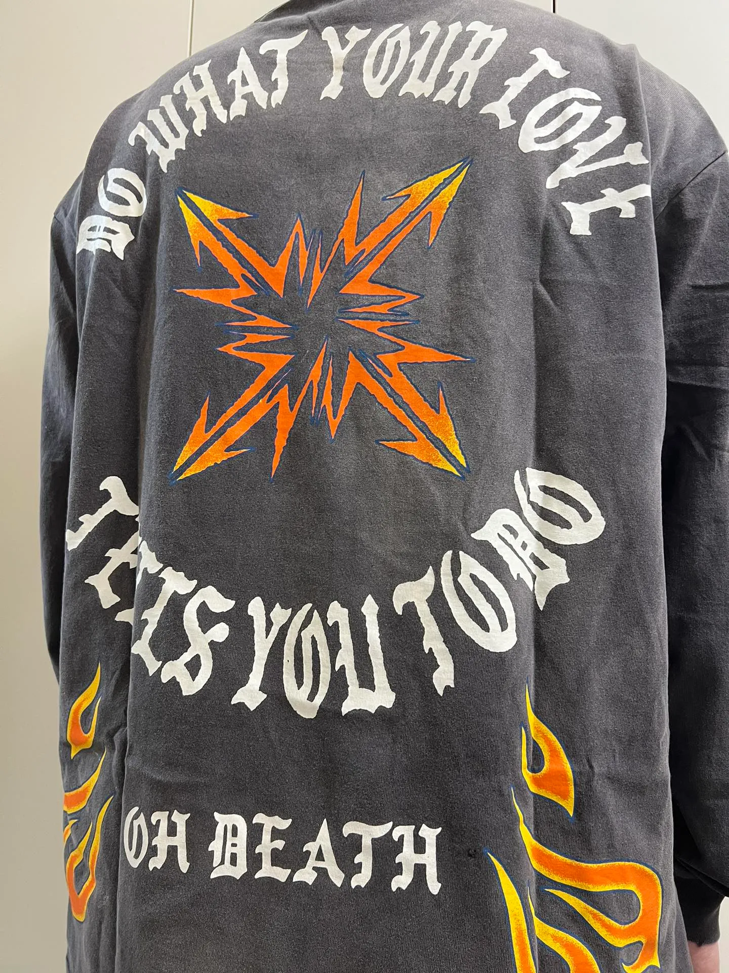 SAINT Mxxxxxx M/AFTER LS_TEE/BLACK Flame arrow Letter M retro distressed long tee Washed black S-XL Tubular fabric Assute ready-made garments dyed The whole piece is sprayed with horse-hair spray and then sprayed again to fade the color. The collar and cuffs are frayed. Many places are frayed. Extra large printing position. Very difficult to print. Complete accessories. With little angel anti-counterfeiting label.